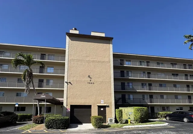 a front view of a building with streets and trees