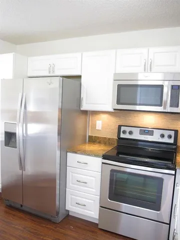 a kitchen with granite countertop white cabinets and stainless steel appliances