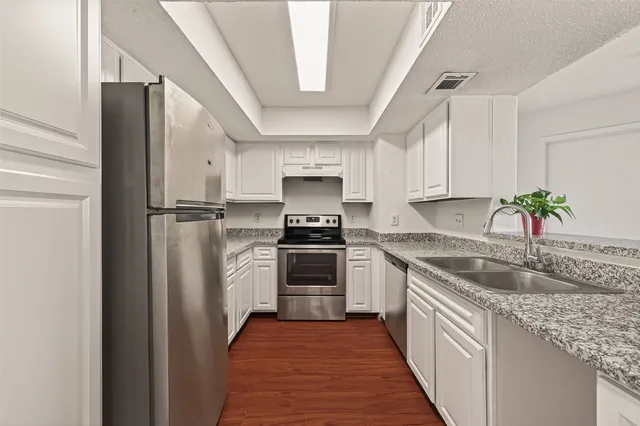 a kitchen with granite countertop a sink stove and refrigerator