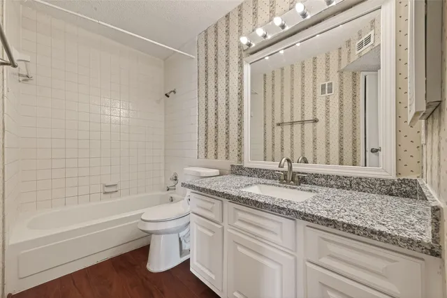 a bathroom with a granite countertop sink a toilet and bathtub