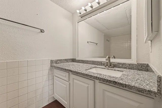 a bathroom with a granite countertop sink and a mirror