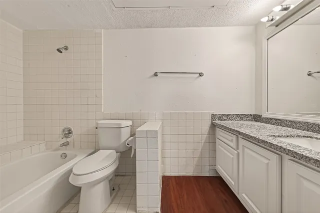 a bathroom with a granite countertop toilet a sink and a bathtub