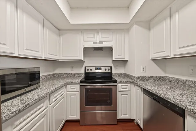 a kitchen with granite countertop white cabinets and stainless steel appliances
