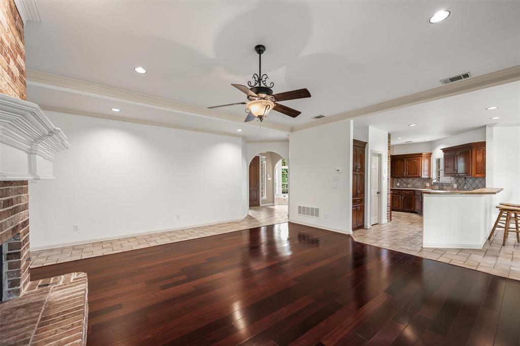 5607 Ranger Drive Rockwall, TX 75032 - Photo 14 of 40 Spacious living area featuring rich wood-finish flooring, a brick fireplace with a white mantel, and crown molding