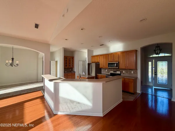 a kitchen with stainless steel appliances granite countertop a refrigerator a sink a stove and white cabinets with wooden floor