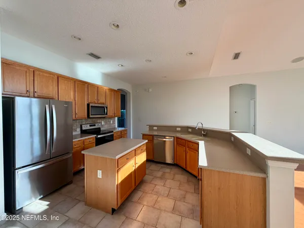 a kitchen with granite countertop a refrigerator and a stove top oven