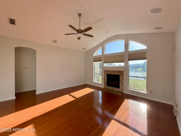 a view of a livingroom with a fireplace a ceiling fan and wooden floor