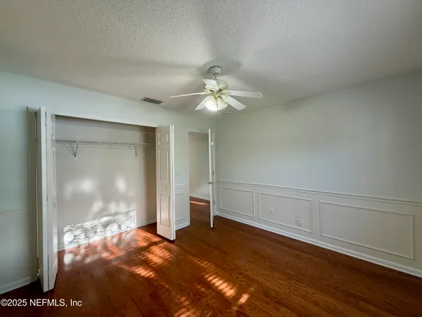 an empty room with wooden floor fan and windows