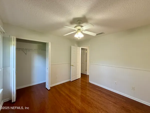 an empty room with wooden floor and ceiling fan