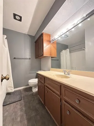 a bathroom with a granite countertop sink a toilet and a mirror