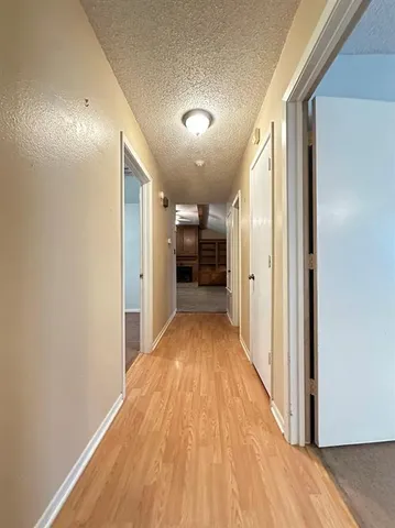 a view of a hallway with wooden floor and a bathroom
