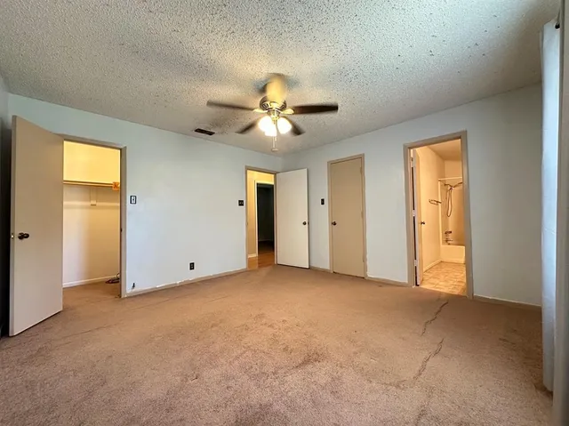 an empty room with closet and a ceiling fan