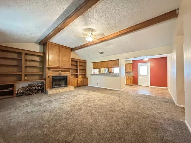 a view of an empty room with a fireplace and a window