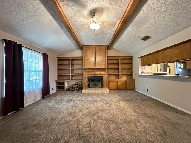 an empty room with a fireplace cabinet and windows