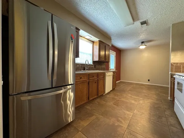 a kitchen with stainless steel appliances granite countertop a refrigerator and a sink