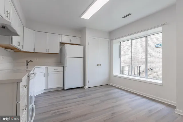 a kitchen with a refrigerator a stove top oven a sink and dishwasher with wooden floor