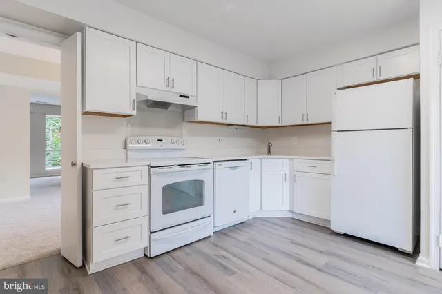 a kitchen with white cabinets white stainless steel appliances and sink