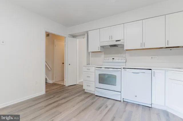 a kitchen with white cabinets and white appliances