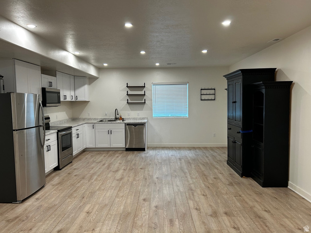 315 South Sherman Street Mapleton, UT 84664 - Photo 20 of 30 Open-concept living space featuring a full kitchen with stainless steel appliances, white cabinetry, and light-toned countertops