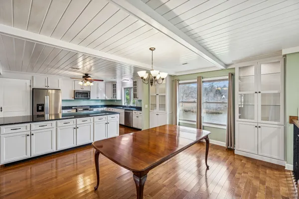 a large white kitchen with lots of counter space dining table and stainless steel appliances