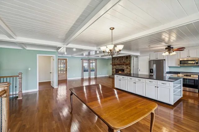 a large white kitchen with lots of counter space dining table and stainless steel appliances