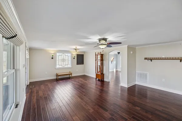 a view of an empty room with wooden floor and a window