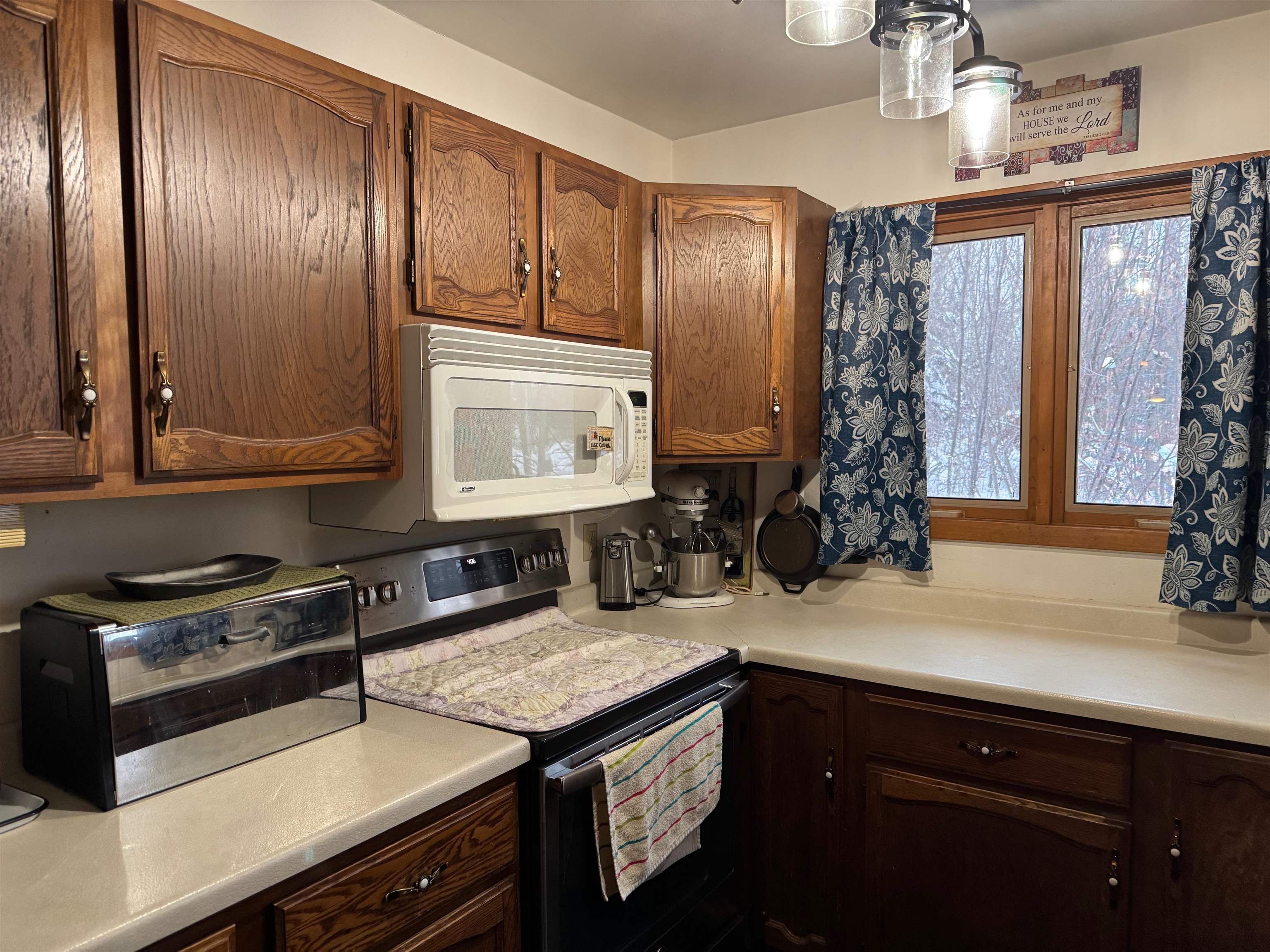 10922 South Stone Road Solon Springs, WI 54873 - Photo 27 of 64 Kitchen with stainless steel electric stove, light countertops, brown cabinetry, and white microwave