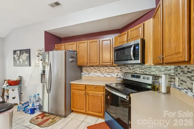 a kitchen with granite countertop cabinets stainless steel appliances a sink and a window