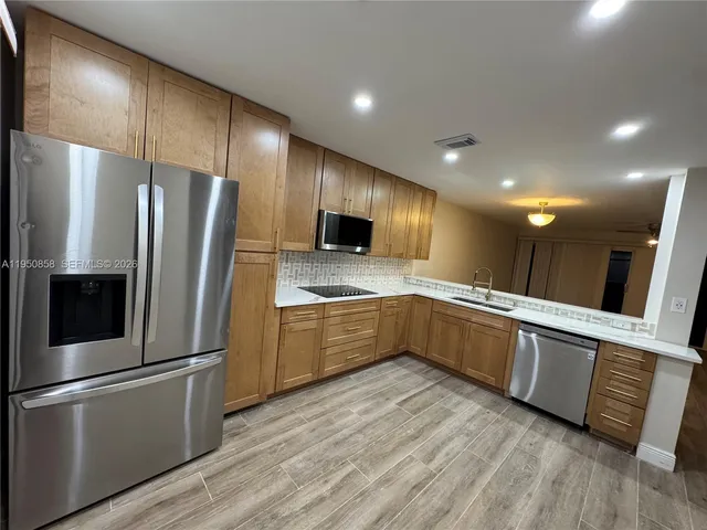 a large kitchen with stainless steel appliances a refrigerator and a stove top oven