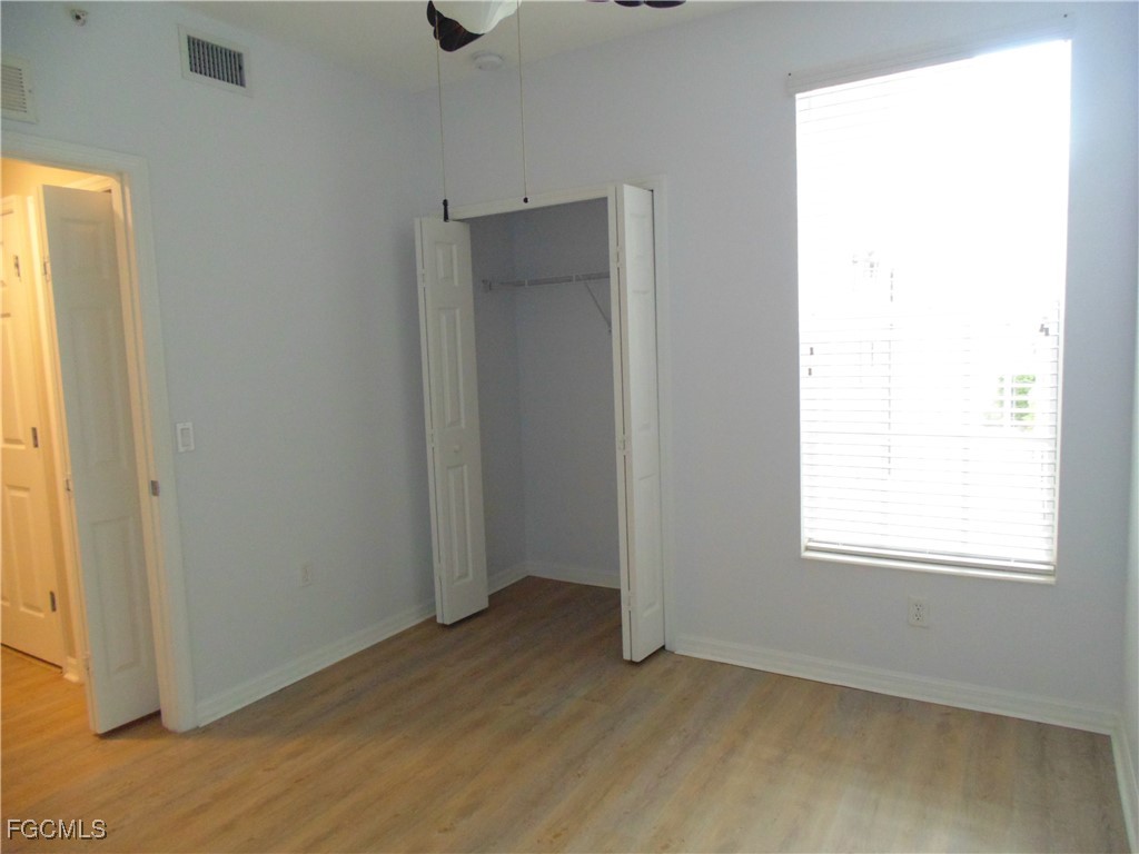 2615 Somerville Loop, Unit 303 Cape Coral, FL 33991 - Photo 25 of 40 a view of an empty room with wooden floor and a window