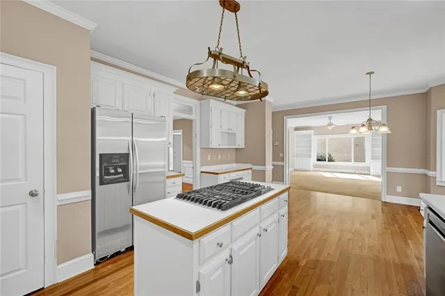 a kitchen with stainless steel appliances a stove a sink dishwasher a refrigerator and a wooden floor