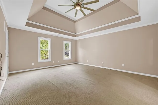 an empty room with a chandelier fan and windows