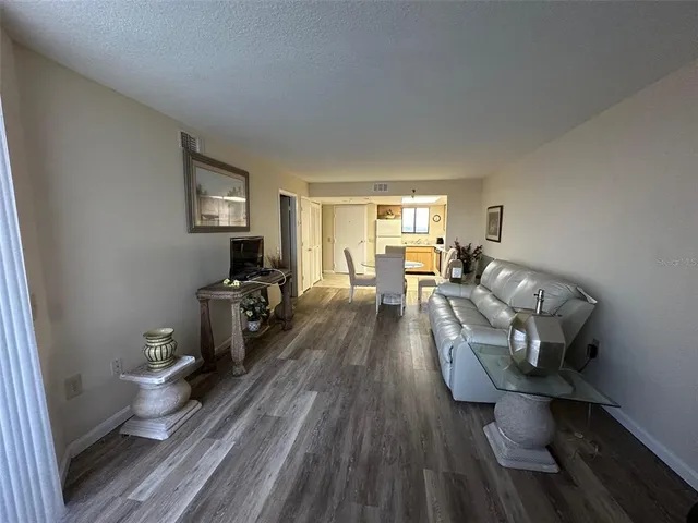 a living room with furniture a flat screen tv and kitchen view