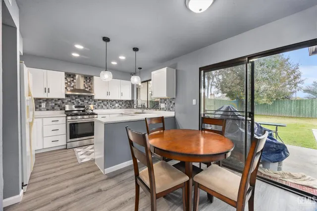 a kitchen with stainless steel appliances granite countertop a stove a refrigerator a kitchen island a table and chairs