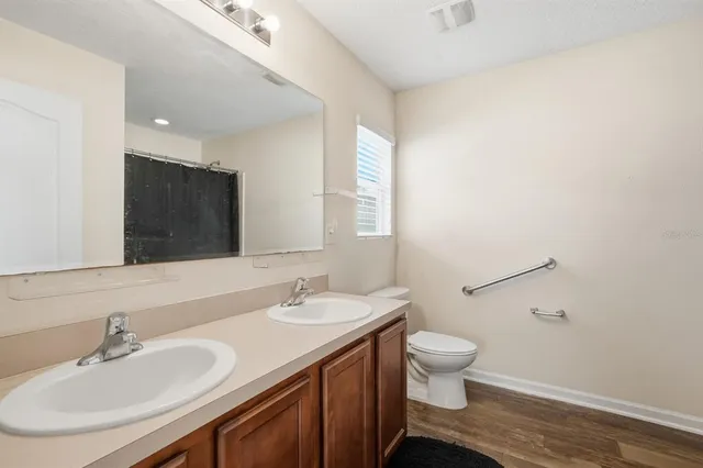 a bathroom with a double vanity sink toilet and mirror