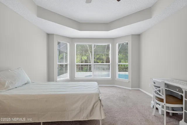 an empty room with chandelier fan and windows