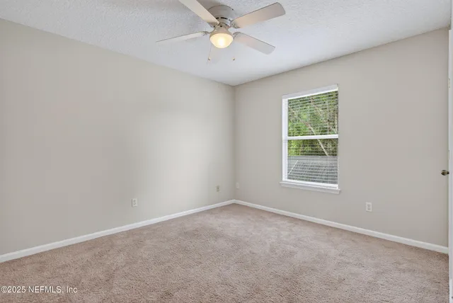 an empty room with a window and a fan