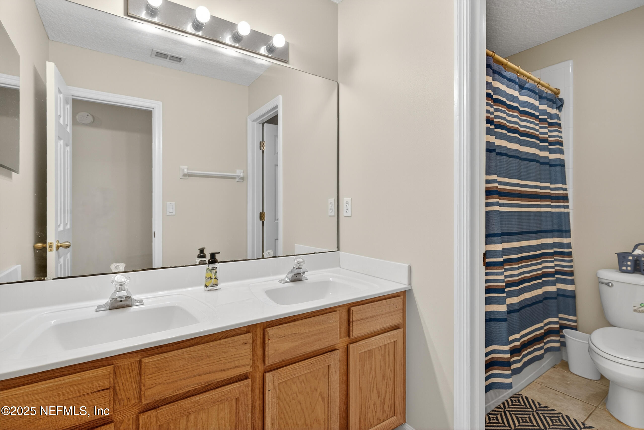 1908 Tuscan Oaks Court Fleming Island, FL 32003 - Photo 24 of 33 a bathroom with a sink a toilet a mirror and shower curtain