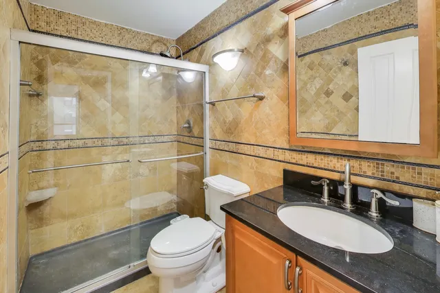 a bathroom with a granite countertop sink toilet and a mirror