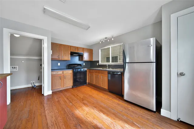 a kitchen with wooden floors stainless steel appliances and refrigerator