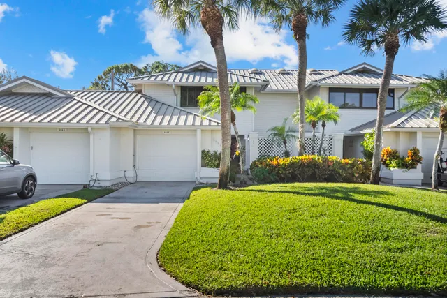 a view of a house with a yard and potted plants