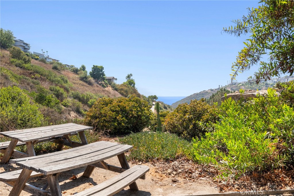 2072 Hidden Valley Canyon Road Laguna Beach, CA 92651 - Photo 22 of 26 a view of a patio with a table and chairs under an umbrella