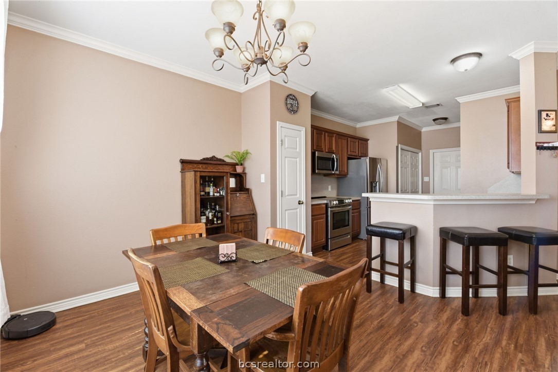 1425 West Villa Maria Road, Unit 605 Bryan, TX 77801 - Photo 14 of 46 Dining space featuring crown molding, dark wood-type flooring, and a chandelier