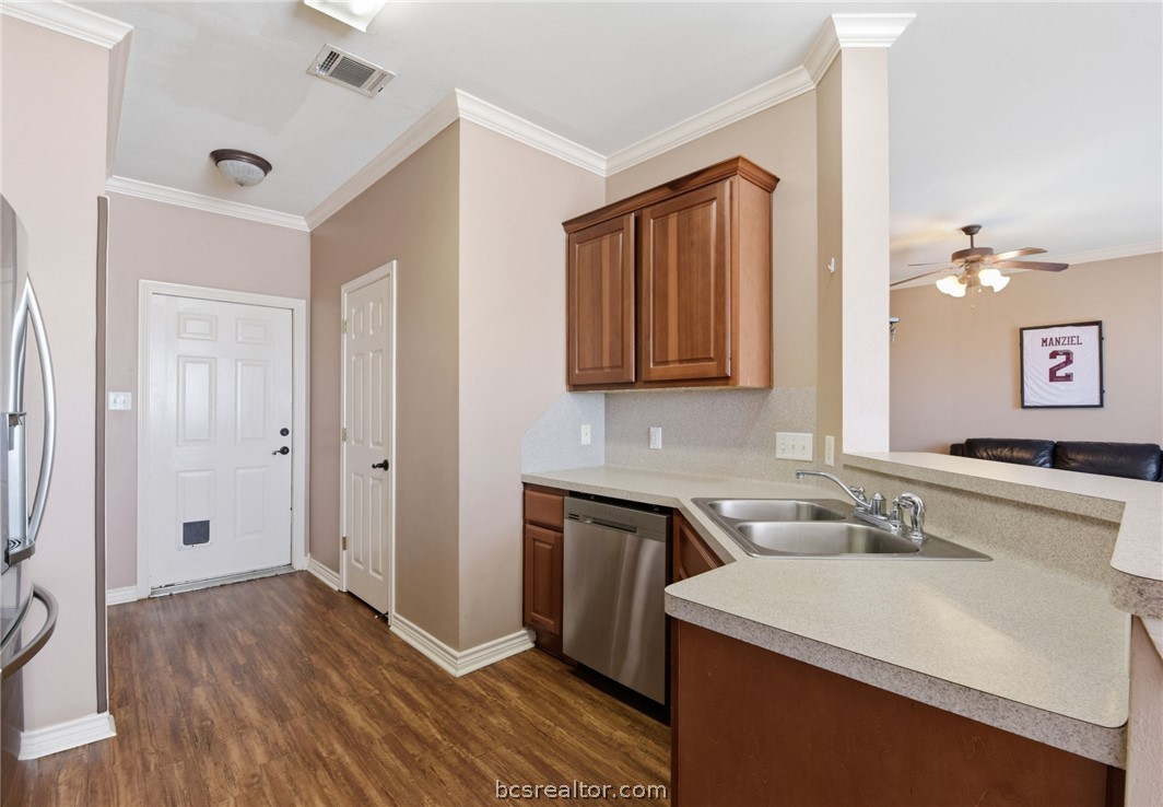 1425 West Villa Maria Road, Unit 605 Bryan, TX 77801 - Photo 17 of 46 Kitchen featuring crown molding, wood finish cabinets, stainless steel appliances, dark wood finished floors, and a peninsula