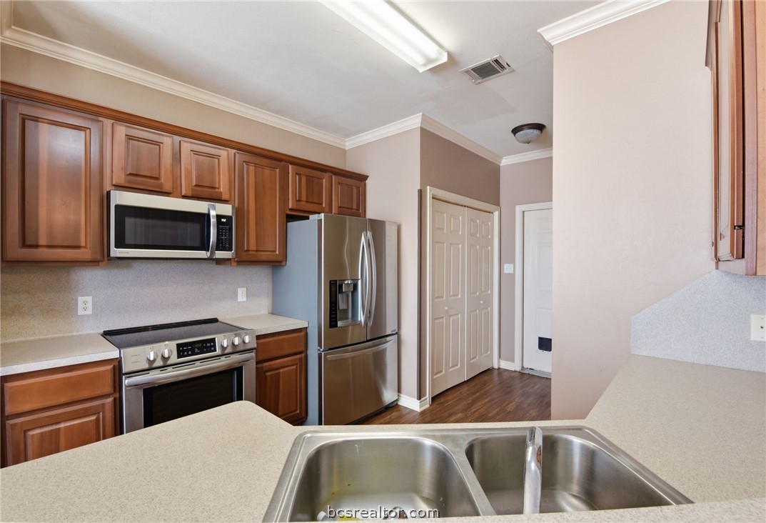 1425 West Villa Maria Road, Unit 605 Bryan, TX 77801 - Photo 18 of 46 Kitchen featuring stainless steel appliances, ornamental molding, light countertops, and dark wood-type flooring