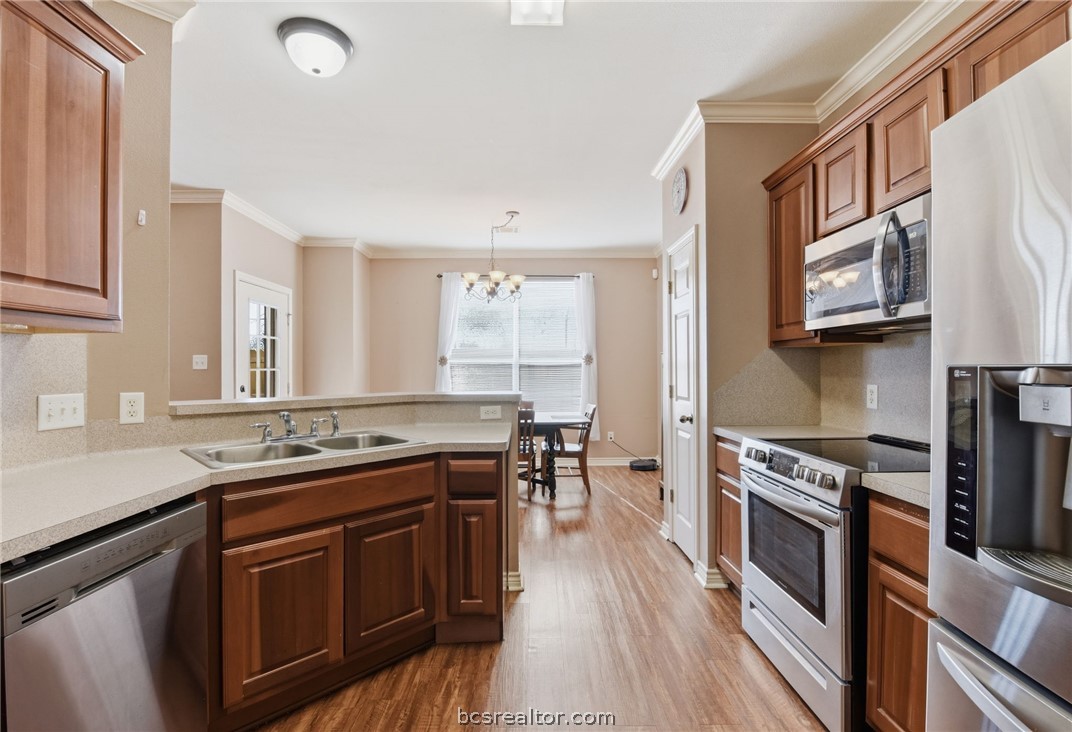 1425 West Villa Maria Road, Unit 605 Bryan, TX 77801 - Photo 19 of 46 Kitchen featuring stainless steel appliances, decorative backsplash, a peninsula, light countertops, and crown molding