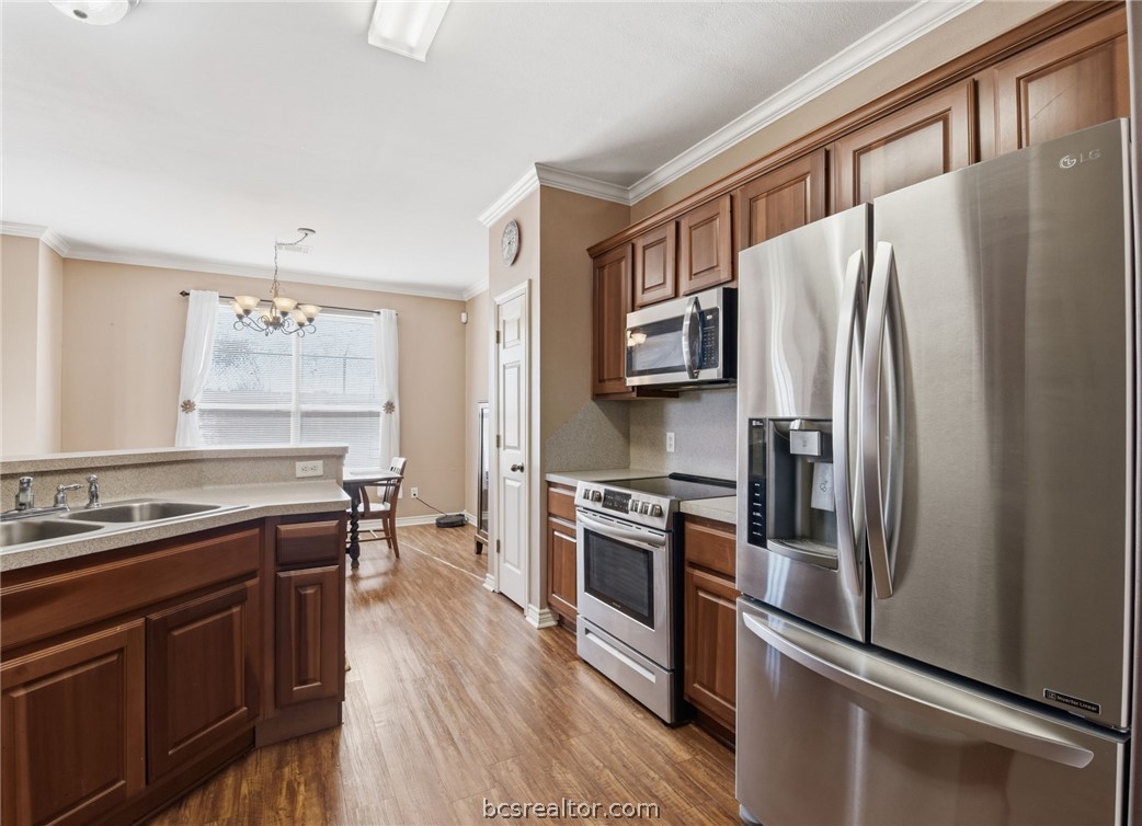 1425 West Villa Maria Road, Unit 605 Bryan, TX 77801 - Photo 20 of 46 Kitchen featuring stainless steel appliances, ornamental molding, dark wood-style floors, light countertops, and suspended lighting