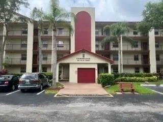 a front view of a building with parking space and plants