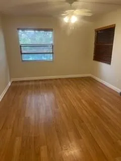 a view of an empty room with wooden floor and a window