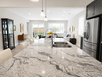 a kitchen with stainless steel appliances kitchen island granite countertop a refrigerator and a sink